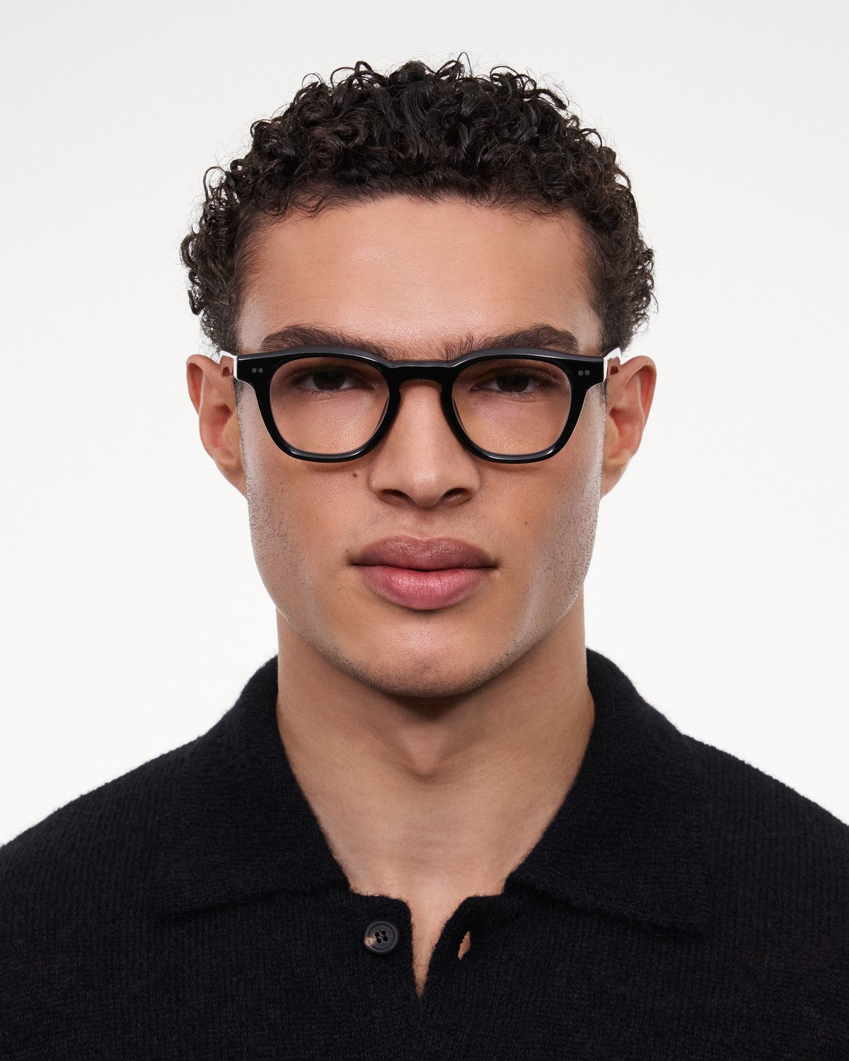 Model wearing CHIMI 01 Core Black Clear eyeglasses with black knit polo shirt.