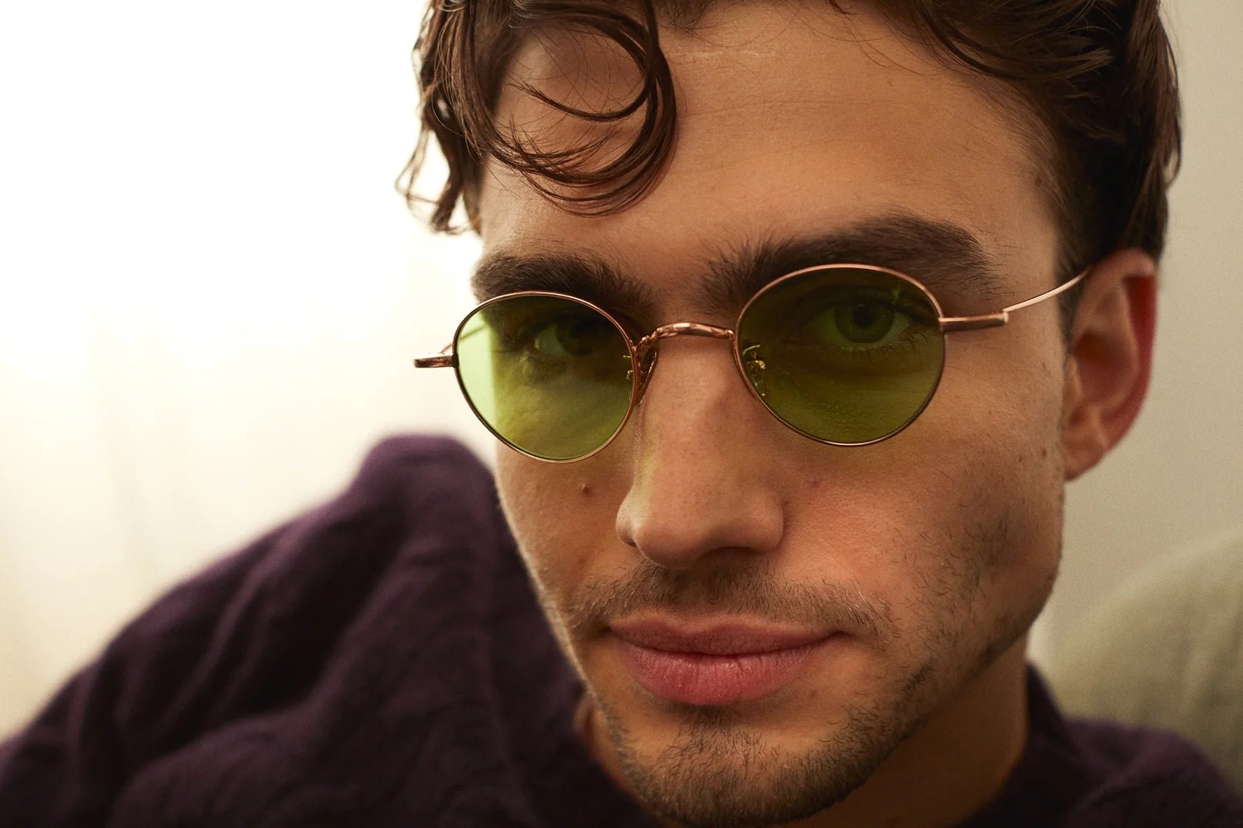 Close-up of a person wearing round sunglasses with a neutral background