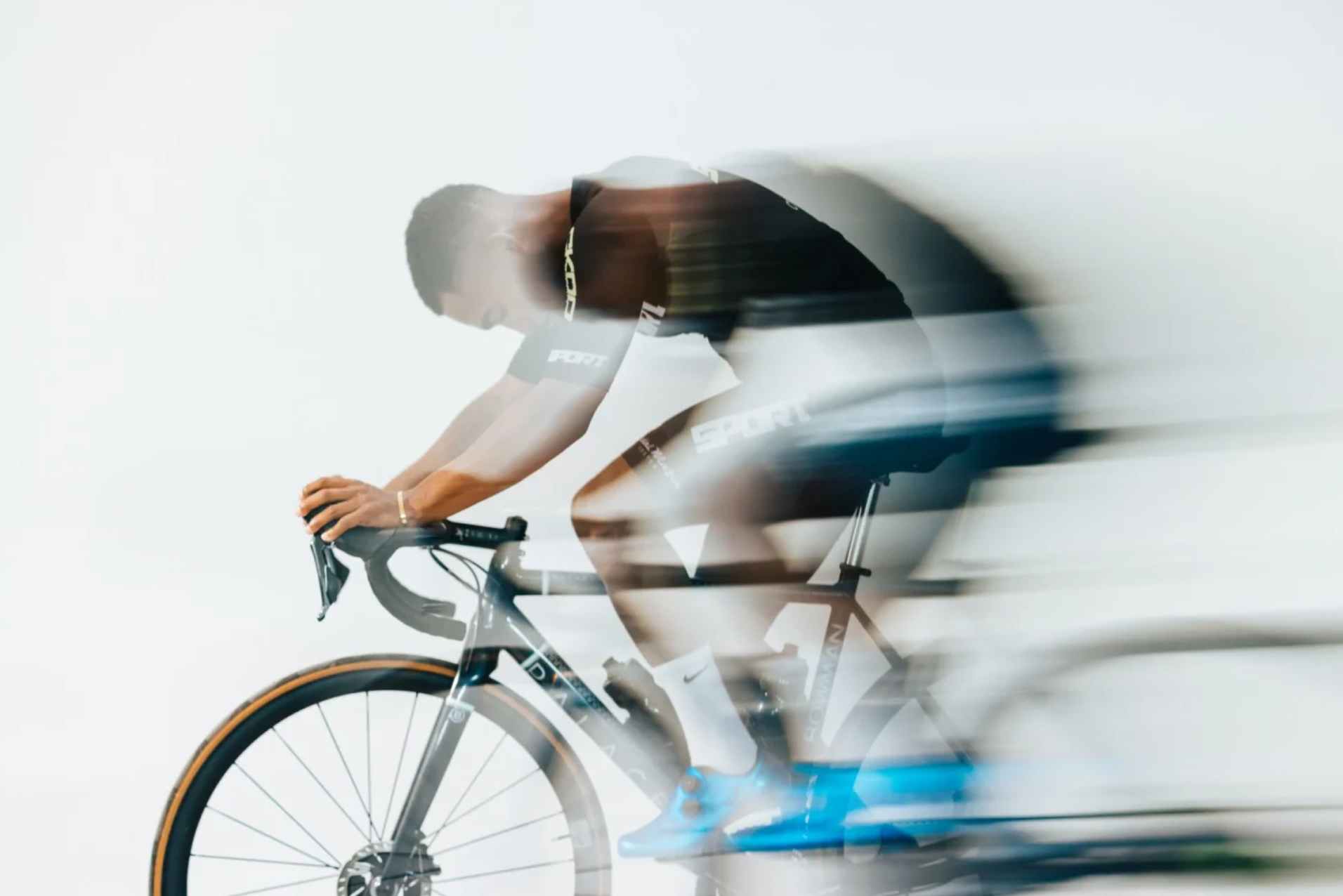 Blurred motion of a cyclist on a road bike against a white background