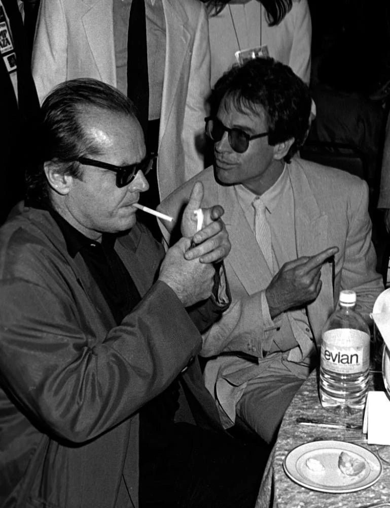 Two men sitting at a table with a bottle of Evian in the background
