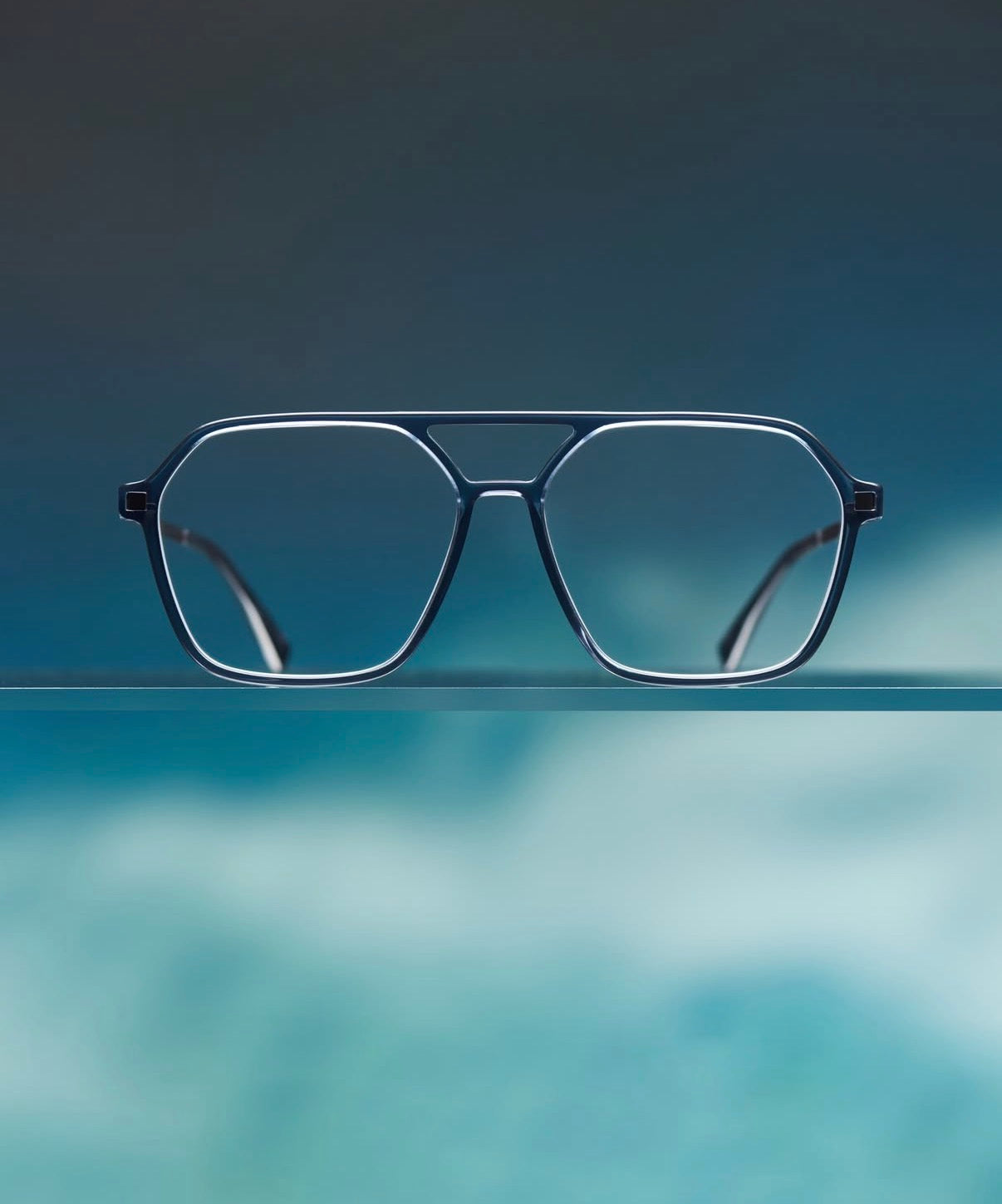 Blue eyeglasses on a reflective surface with a gradient background