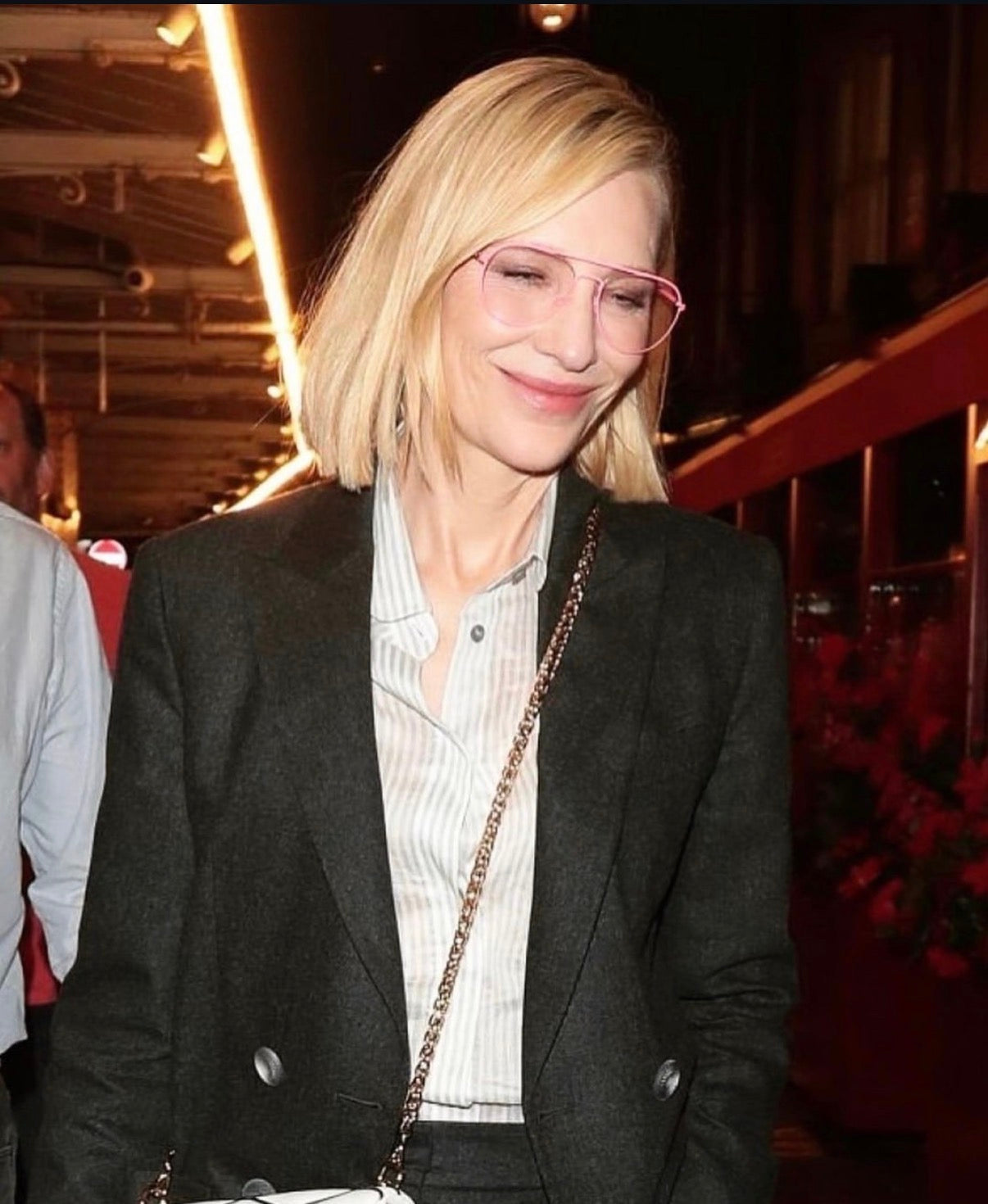 Woman wearing glasses and a dark blazer in an indoor setting
