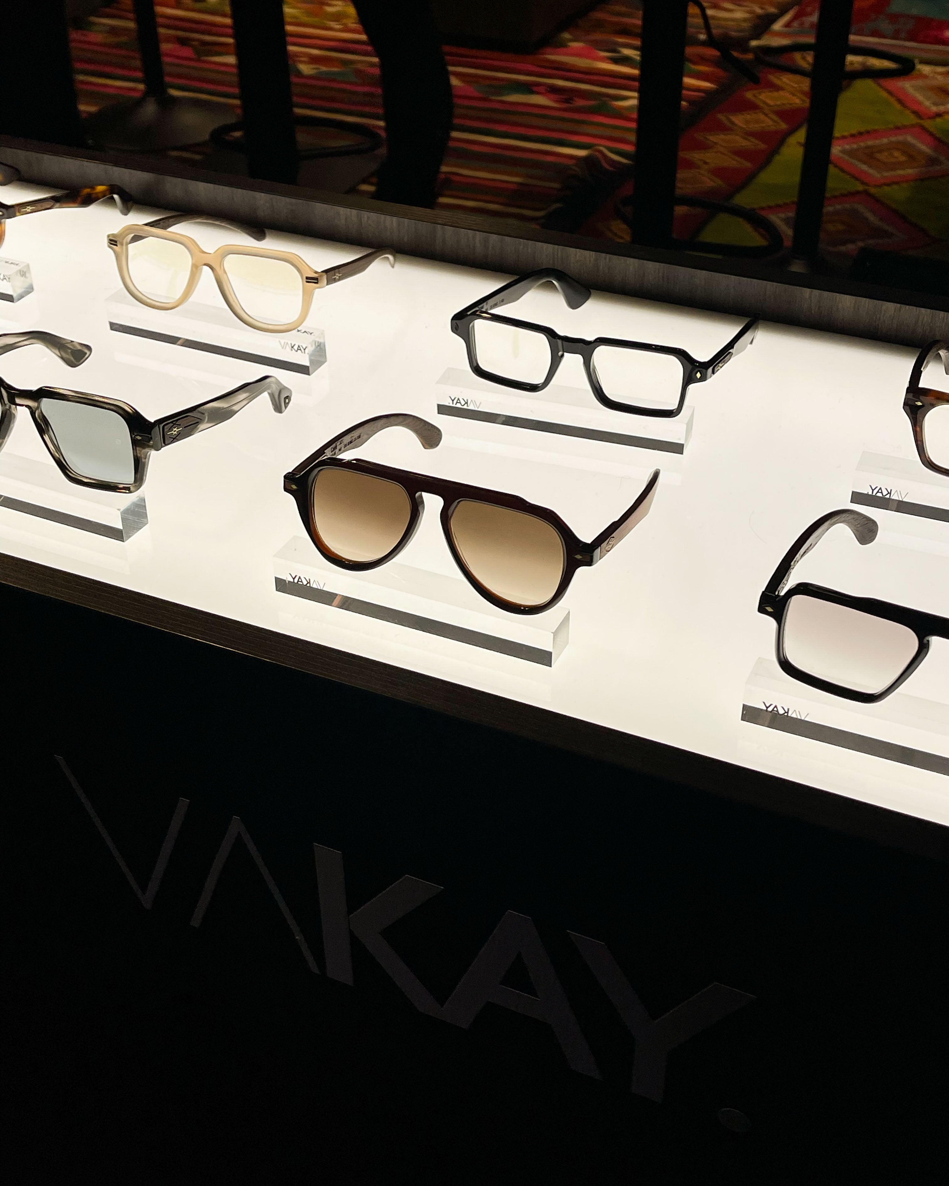 Display of various eyeglasses and sunglasses on a branded stand.