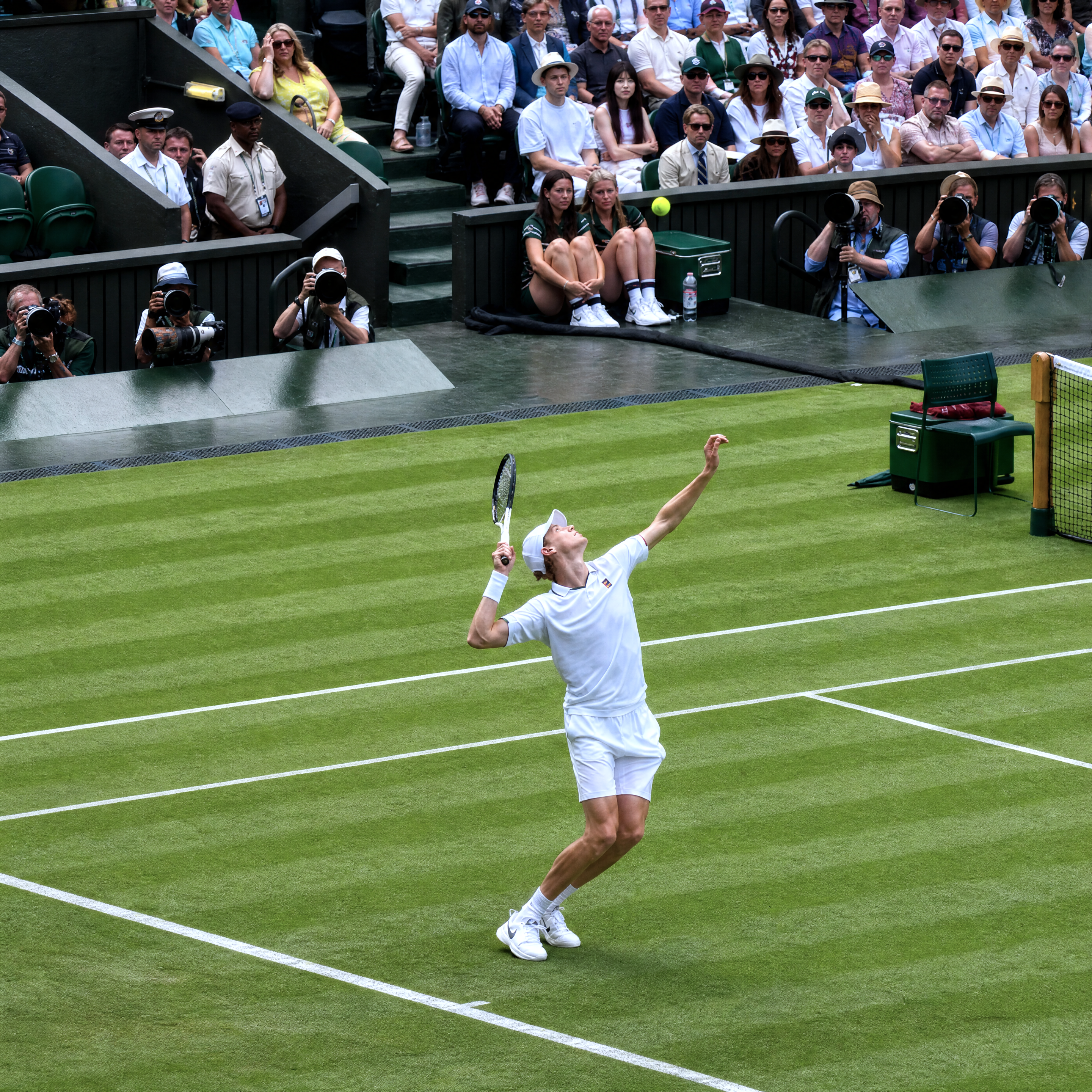 Jannik Sinner serving at centre court Wimbledon on a grass tennis court 