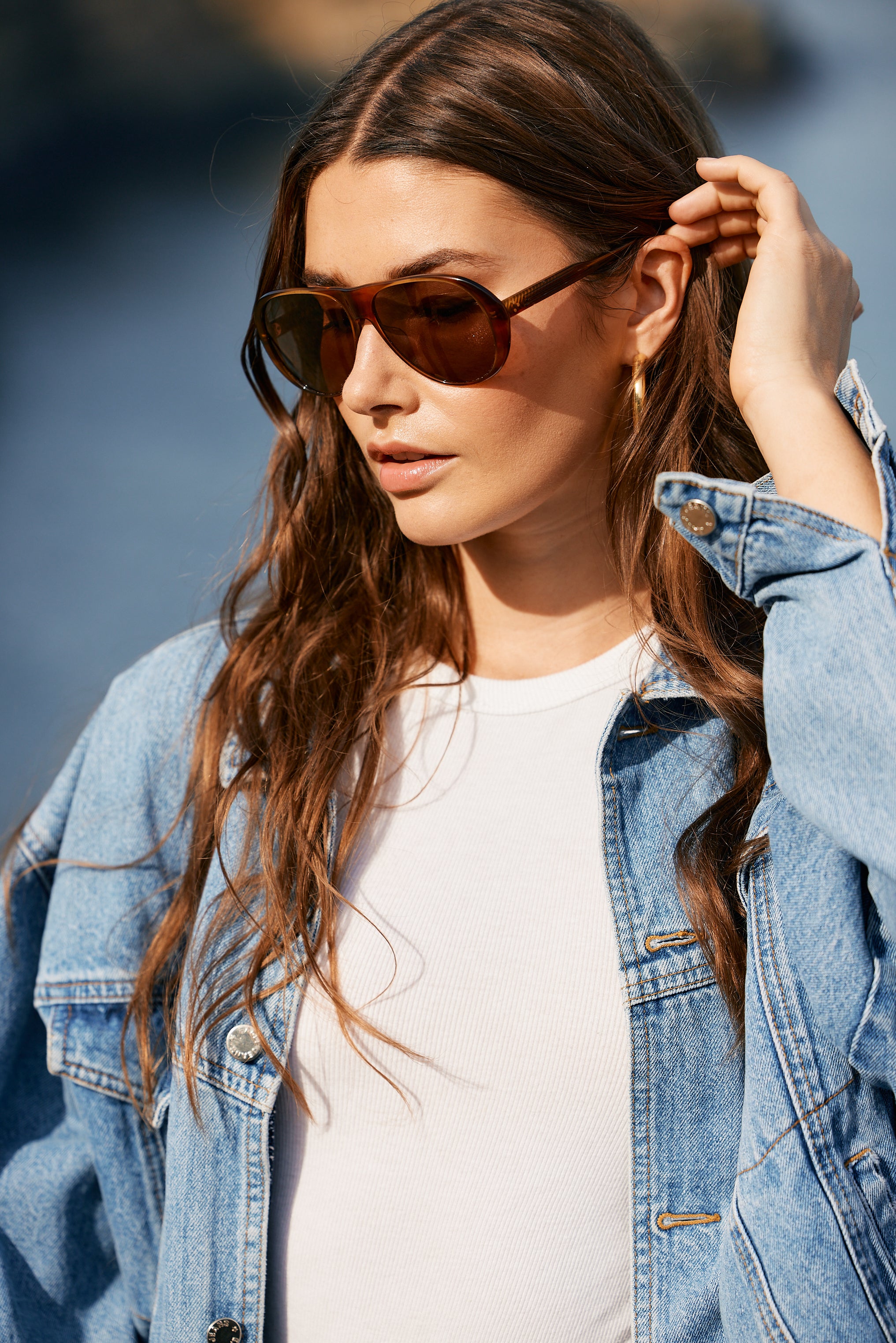 Woman wearing sunglasses and a denim jacket outdoors