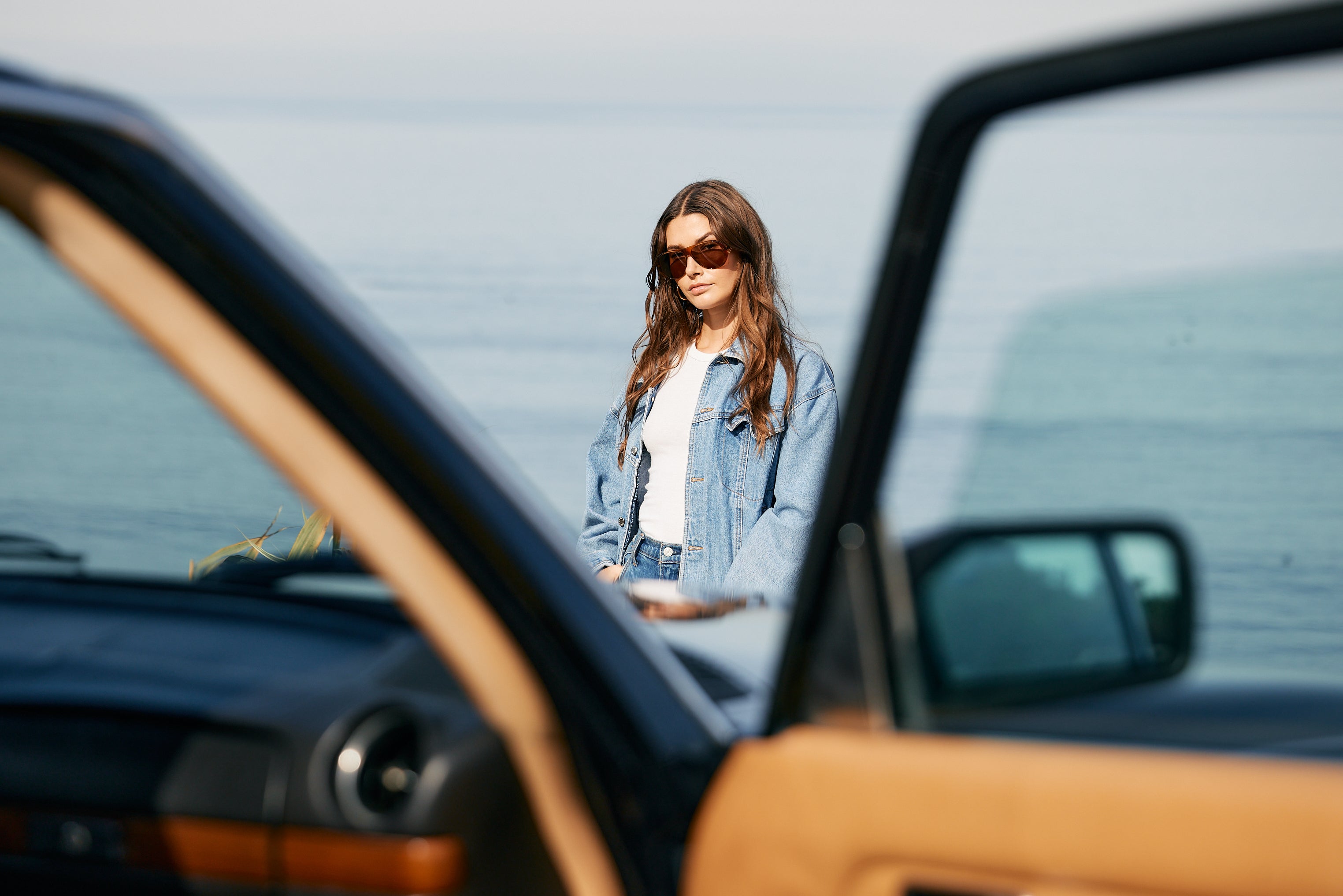 Woman standing next to a car with a blurred background on California Bay