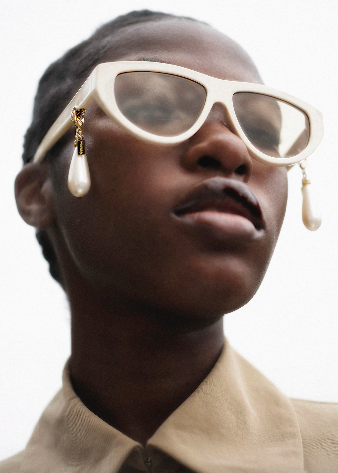 Person wearing large white sunglasses with a neutral background
