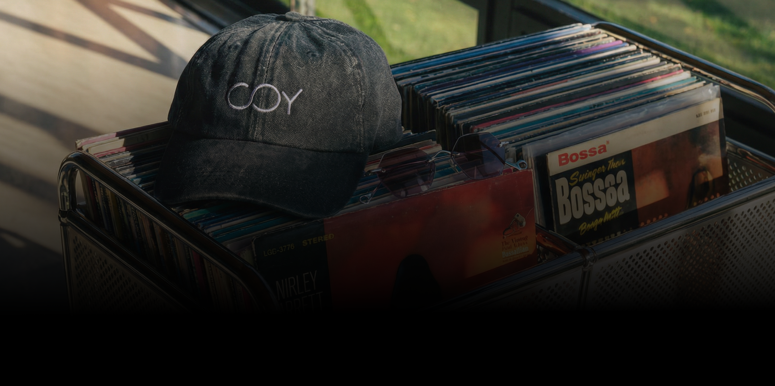 Black cap with 'COY' logo on a stack of cassette tapes.