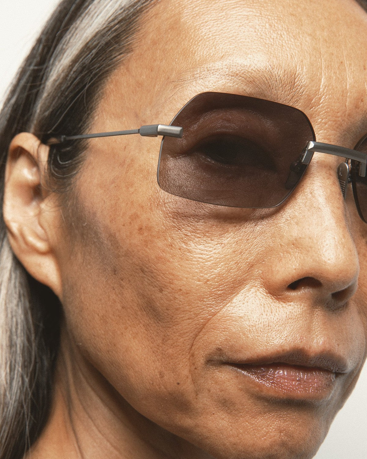 Angled close-up of a model wearing KALEOS Anselm Gun Matte Black Gradient sunglasses.