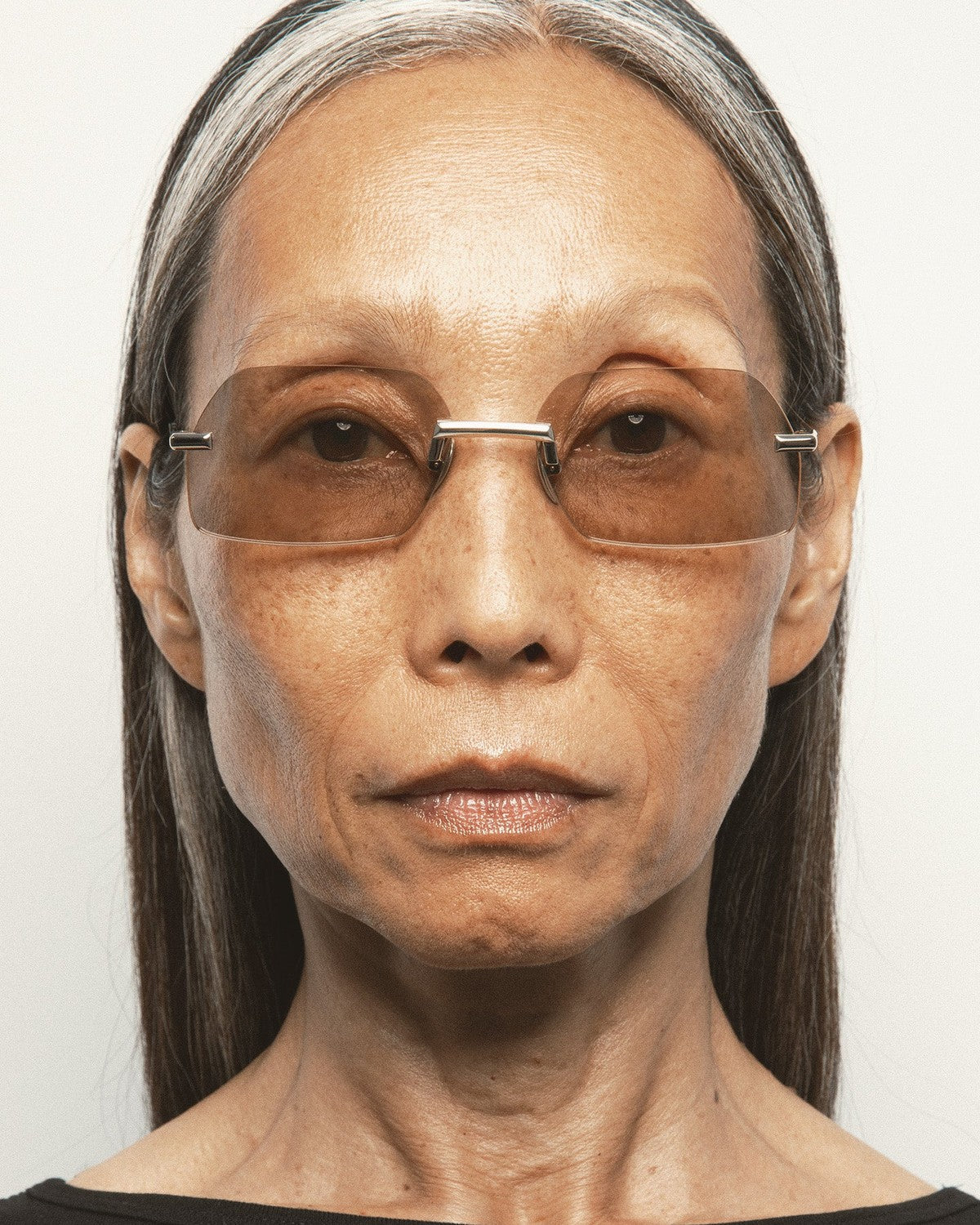 Model wearing KALEOS Anselm Gold Brown Photochromic sunglasses, front view.