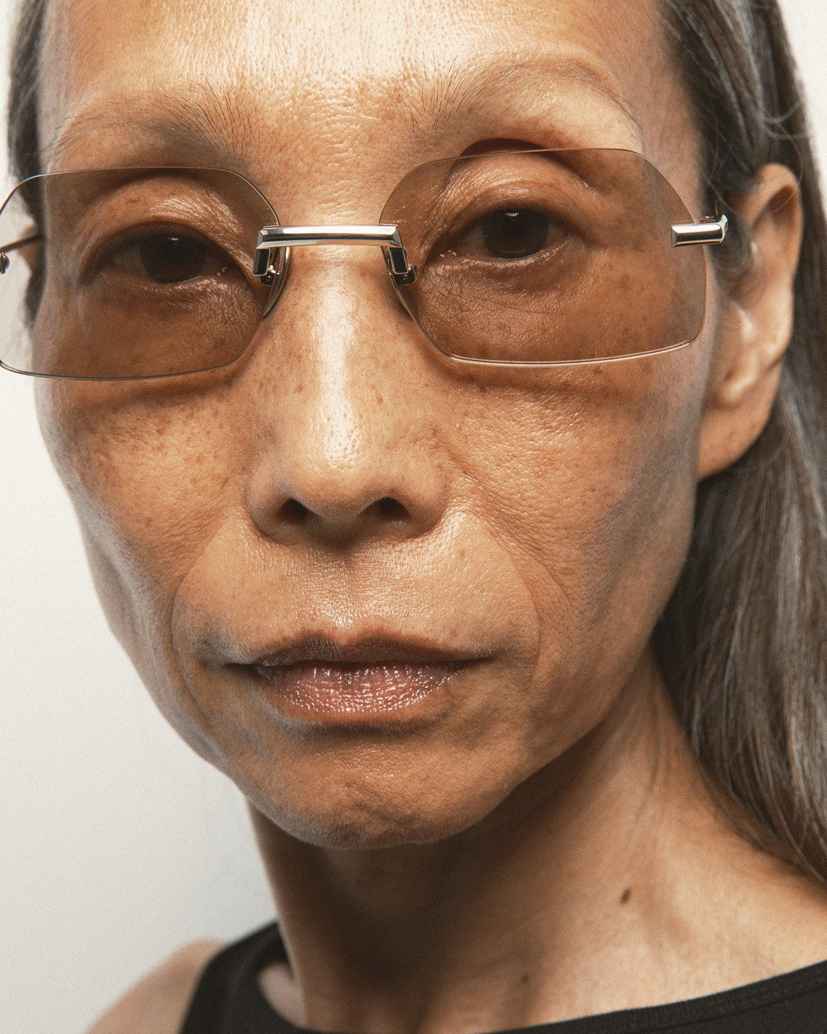 Close-up of model wearing KALEOS Anselm Gold Brown Photochromic sunglasses.