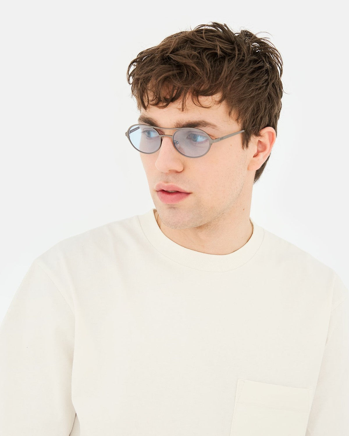 Model wearing RETROSUPERFUTURE Bird Blue-Gun sunglasses with a cream sweatshirt.