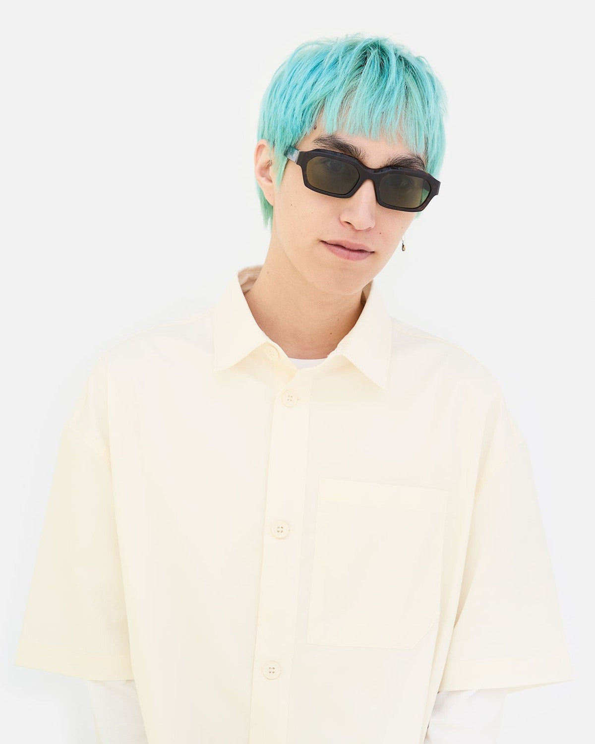 Model wearing RETROSUPERFUTURE Boletus 3627 sunglasses with turquoise hair and cream shirt.