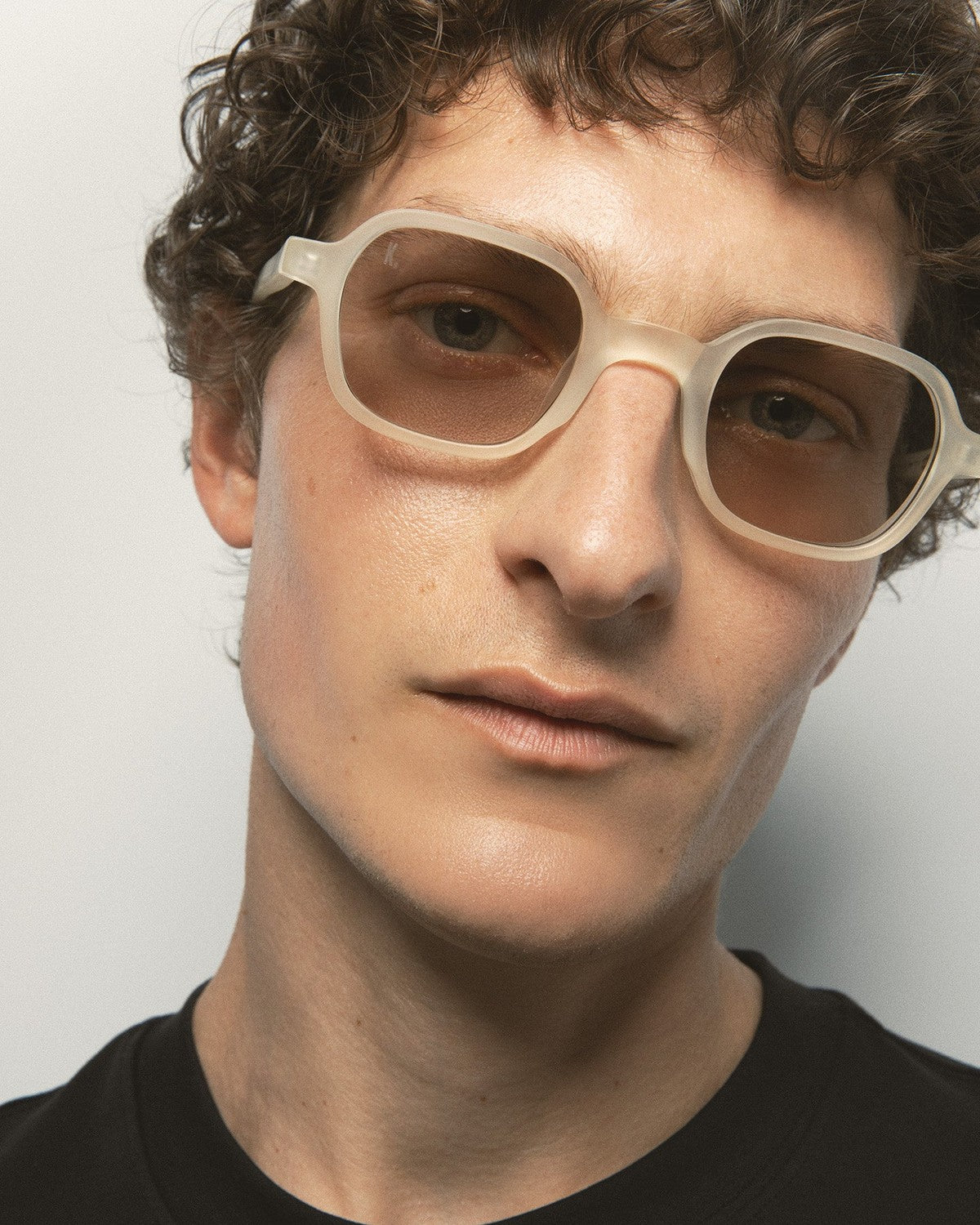 Angled close-up of model wearing KALEOS Castillo Crystal Yellow Matte Brown sunglasses.