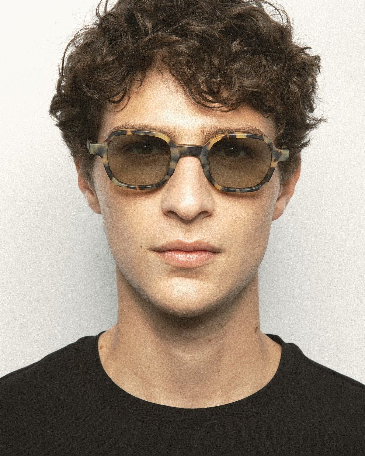 Model wearing KALEOS Castillo Spotted Havana Matte Green Photochromic sunglasses, straight-on view.