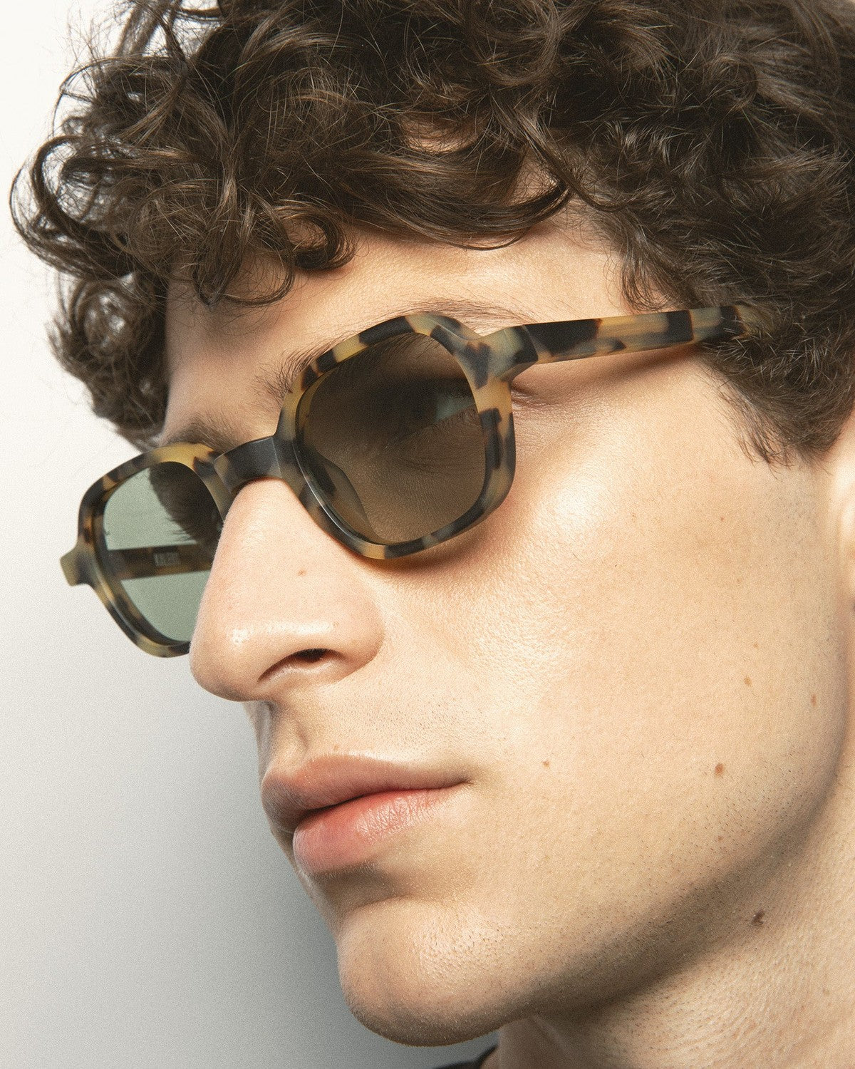 Model wearing KALEOS Castillo Spotted Havana Matte Green Photochromic sunglasses, side angle view.