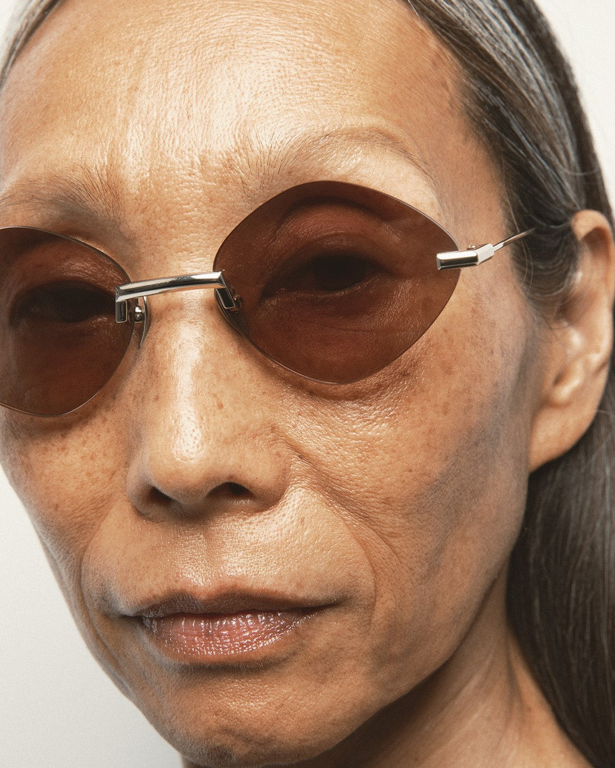 Close-up of model wearing KALEOS Cepeda Gold Brown Degrade sunglasses.