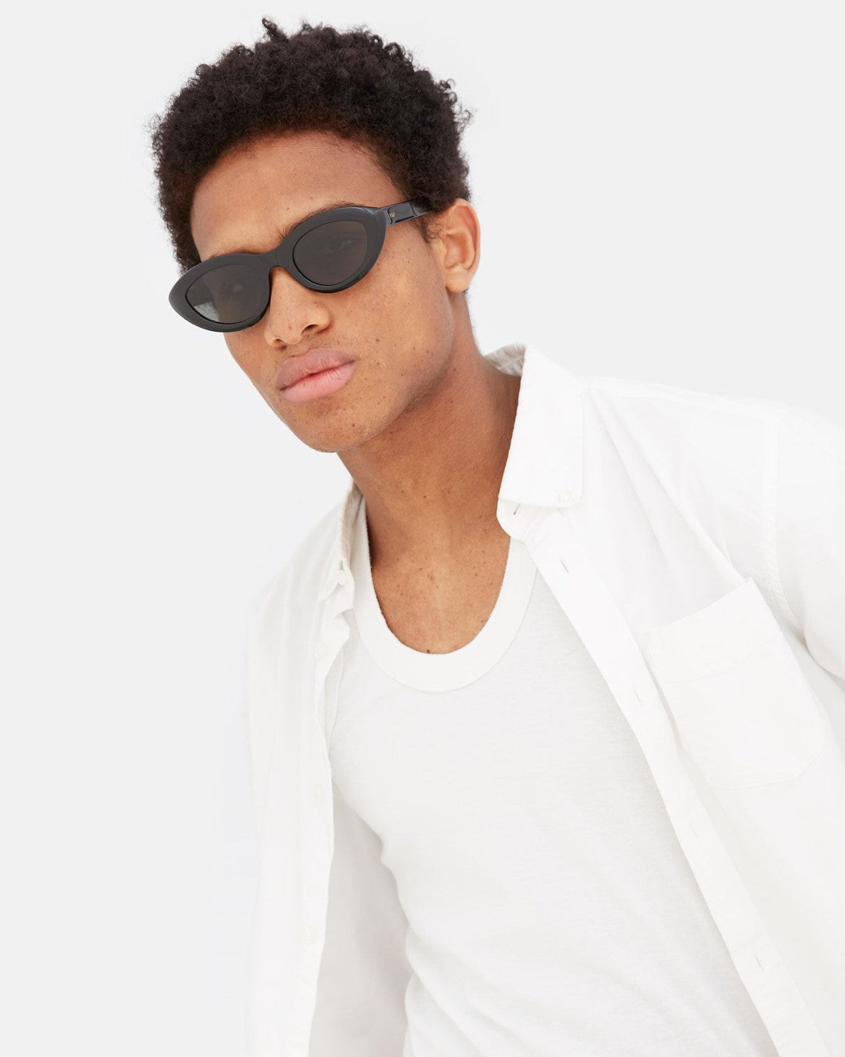 Model wearing RETROSUPERFUTURE Cocca Black sunglasses in a white outfit.