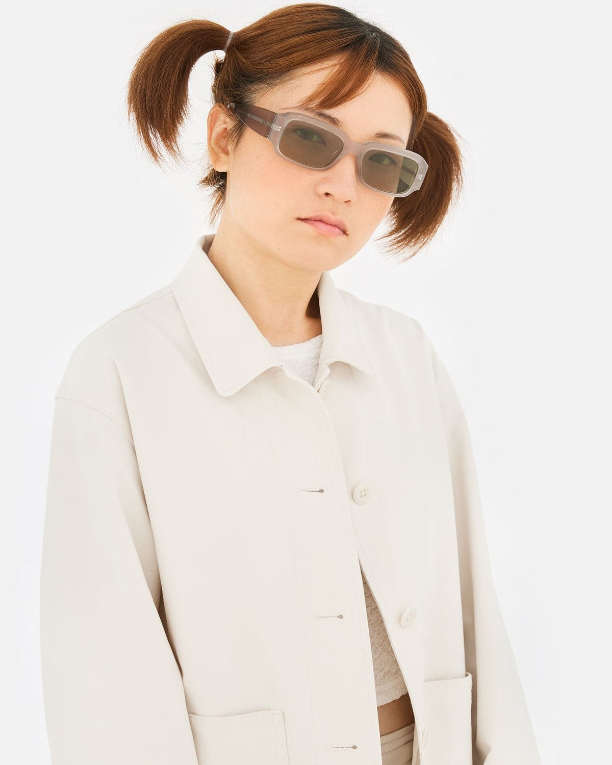 Model wearing RETROSUPERFUTURE Etrusco Light Grey sunglasses with ponytails and light jacket.