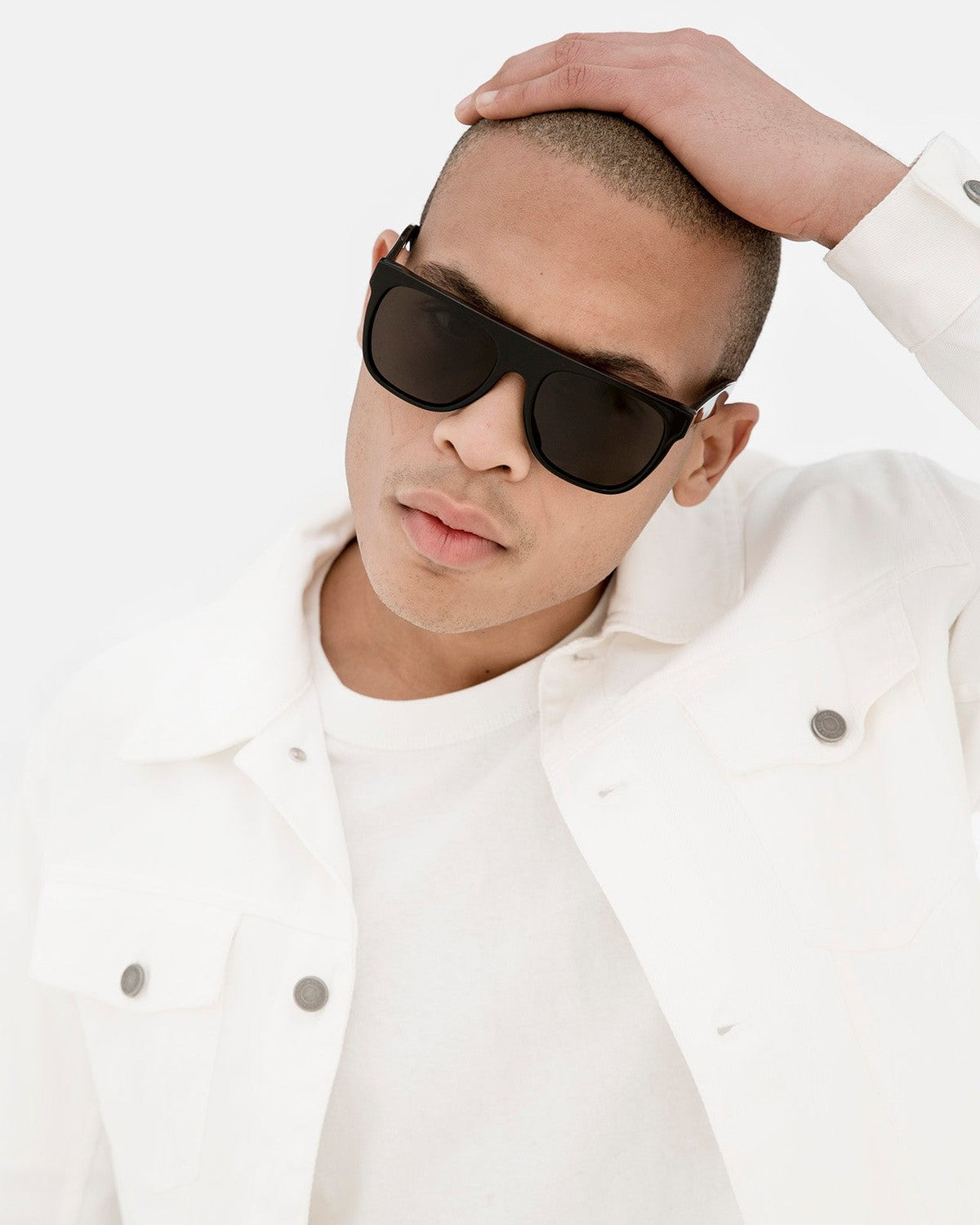 Model wearing RETROSUPERFUTURE Flat Top Black sunglasses in white jacket.