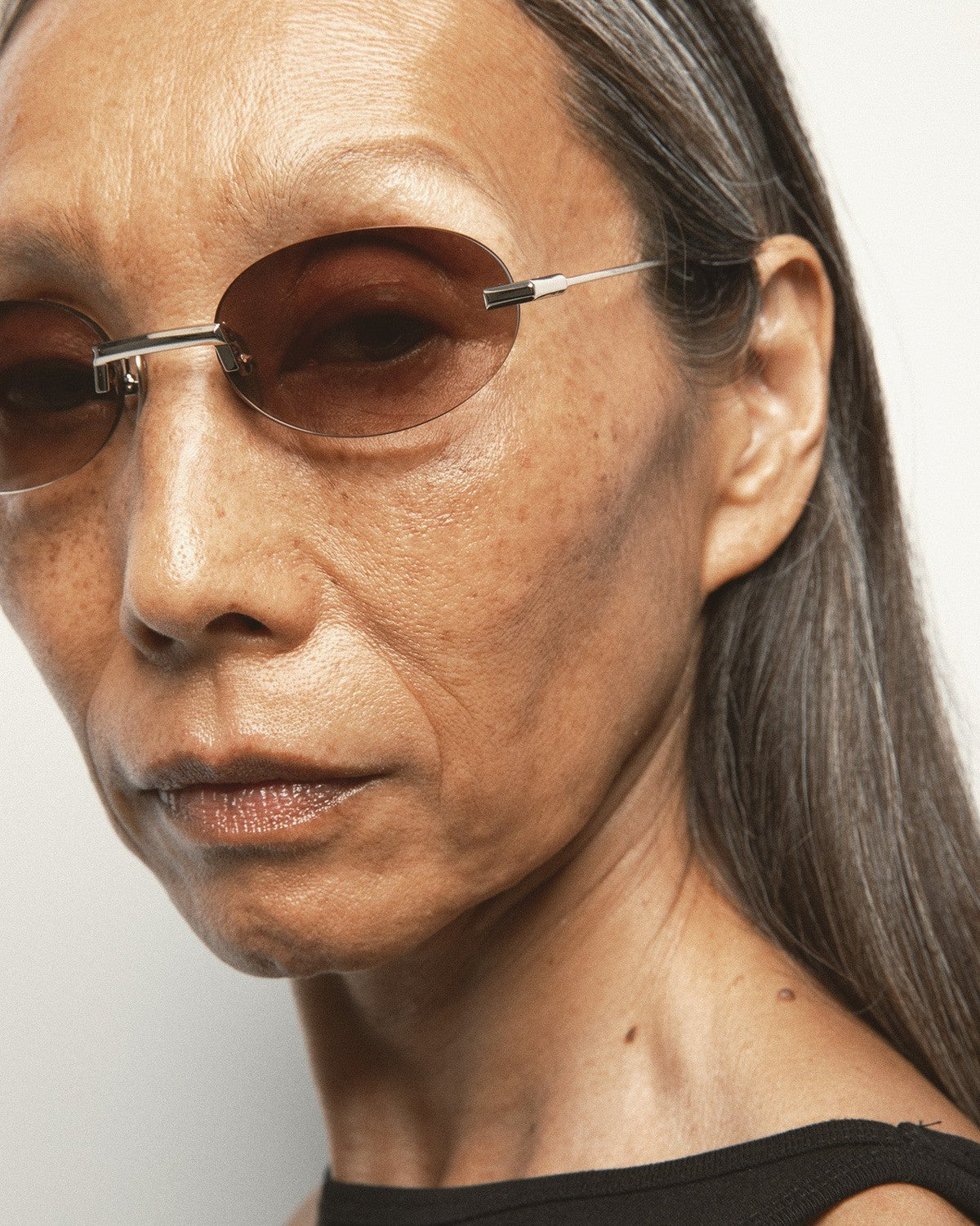 Angled close-up of model wearing KALEOS Fuentes Gold Brown Gradient sunglasses.