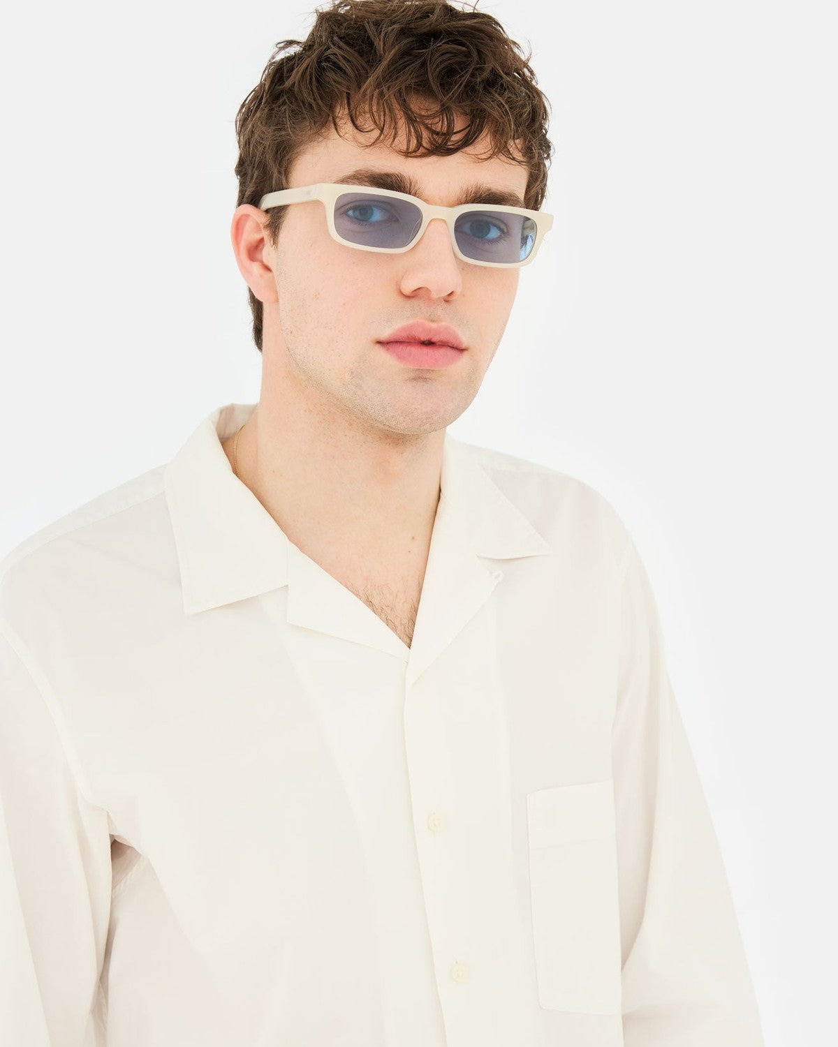 Model wearing RETROSUPERFUTURE Gesto Cremoso sunglasses in an open-collar shirt.