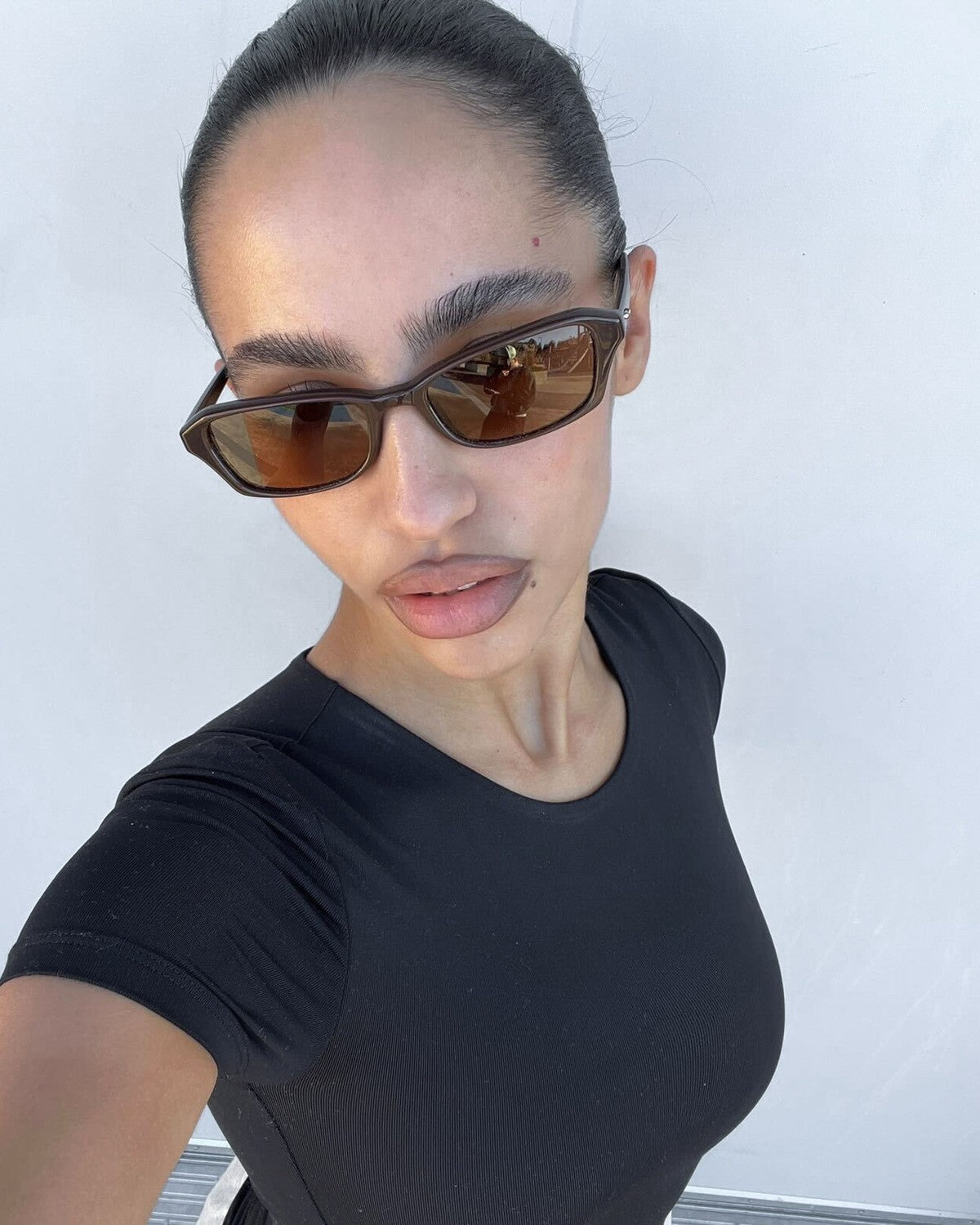 Model wearing CHIMI Iris Brown Brown sunglasses in a selfie pose.