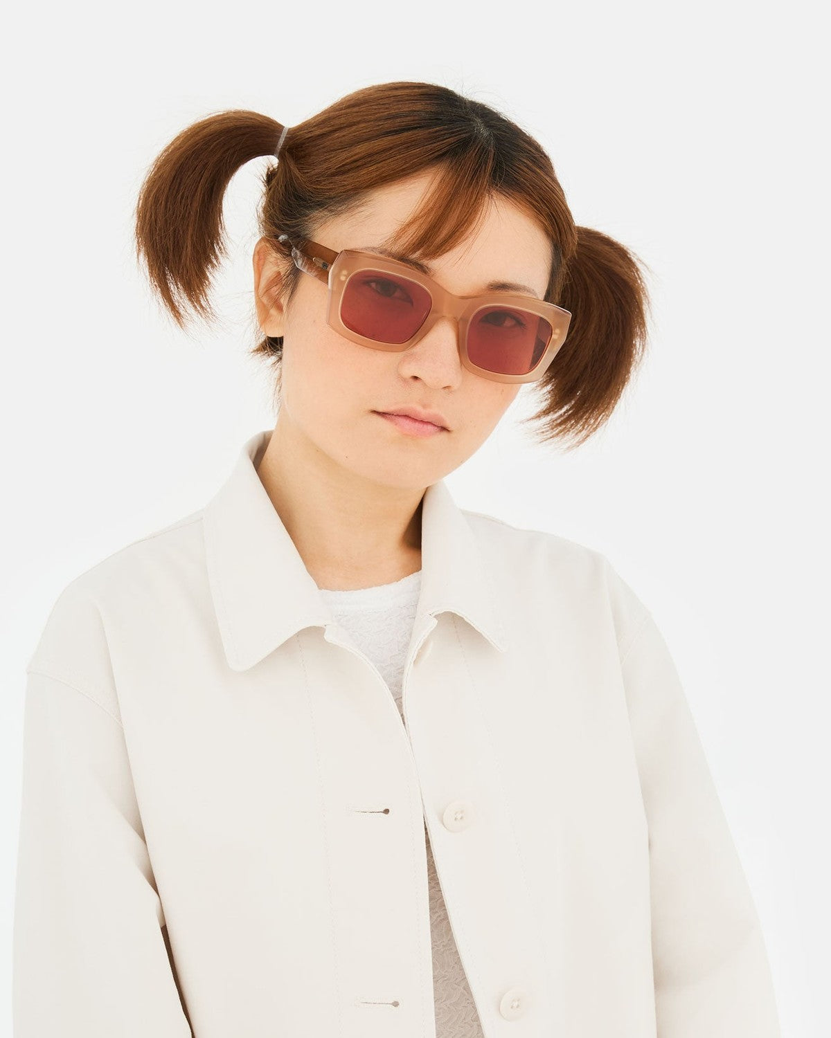 Model wearing RETROSUPERFUTURE Komori Light Brown sunglasses with light jacket and hair in two short ponytails.