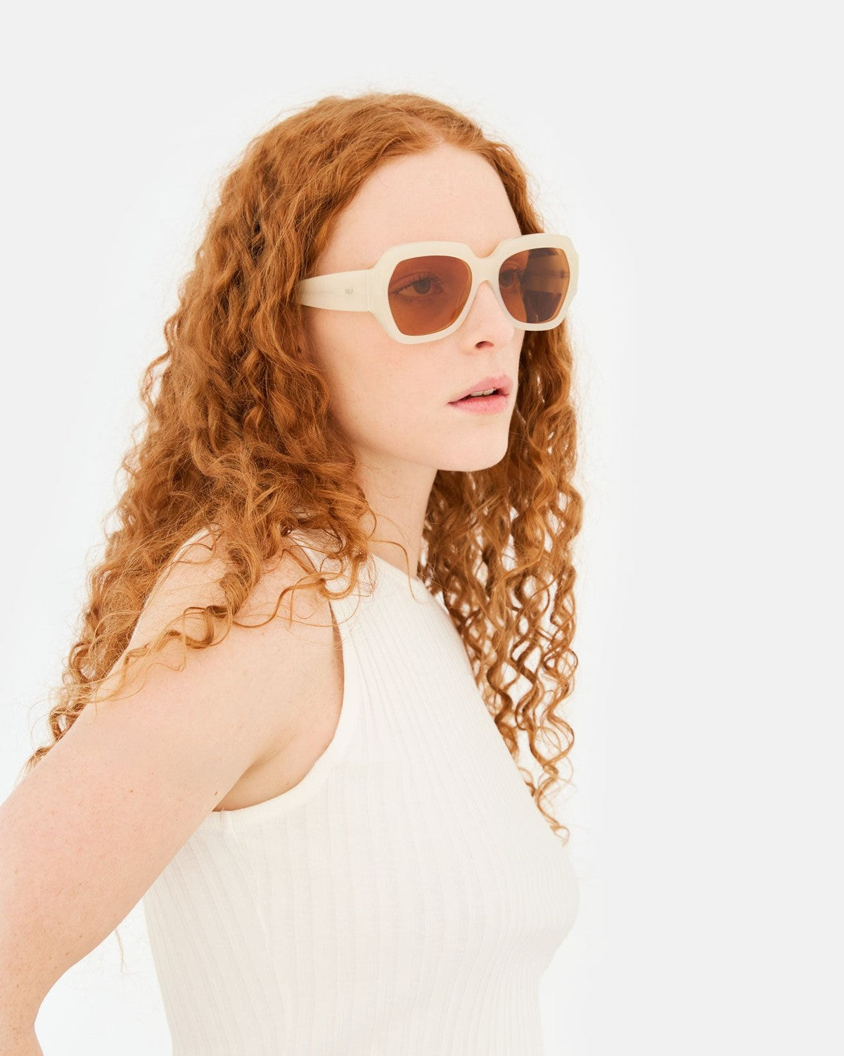 Model wearing RETROSUPERFUTURE Nala Cremoso sunglasses with a white ribbed top.