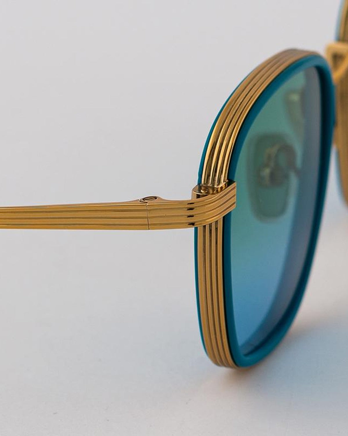 Close-up of the ribbed gold temple and hinge on EYEPETIZER NOMAD C.T-4-43 sunglasses.