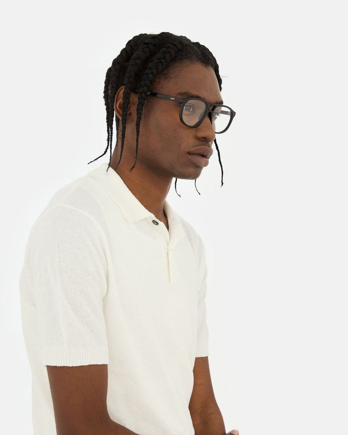 Model wearing RETROSUPERFUTURE Numero 127 Black sunglasses with a white polo shirt, side profile.