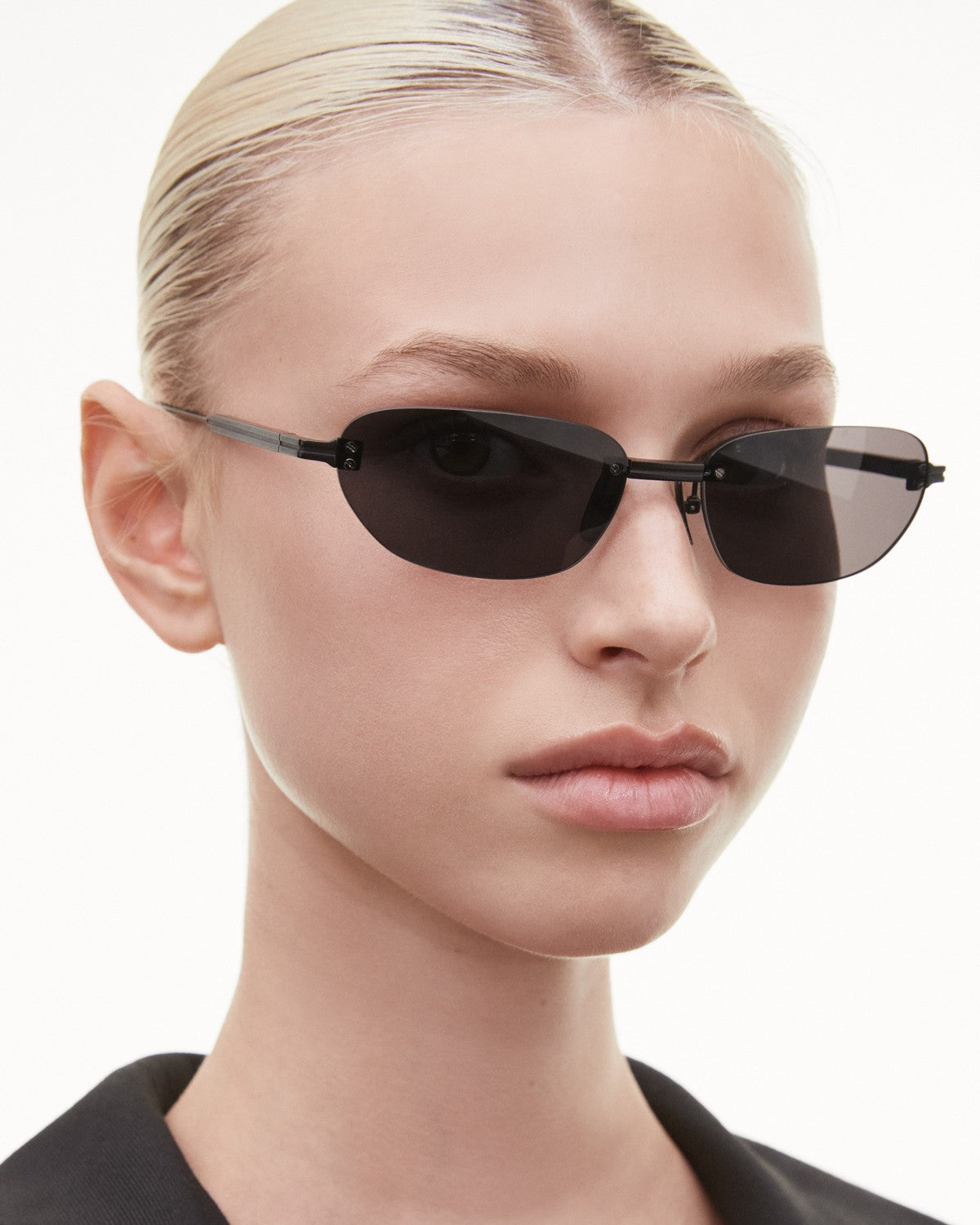 Side angle view of CHIMI Rimless Oval Black Black sunglasses on model.