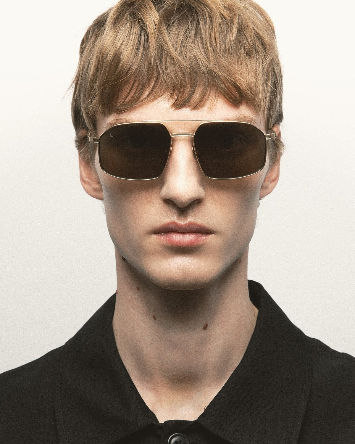 Model wearing KALEOS Ross Gold Green Mineral sunglasses, front view.