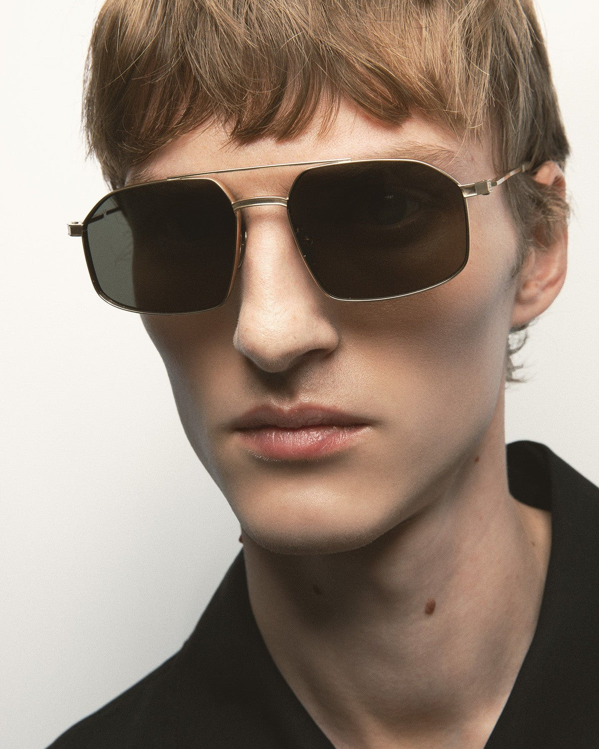 Model wearing KALEOS Ross Gold Green Mineral sunglasses, angled view.