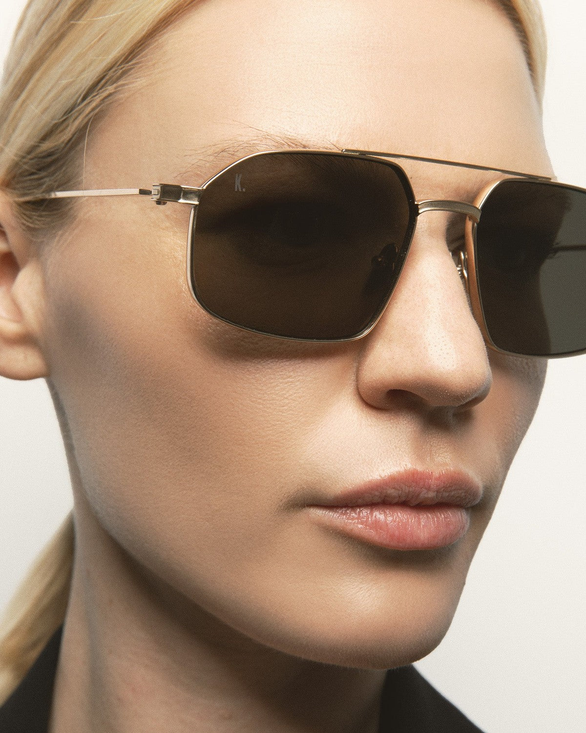 Close-up of model wearing KALEOS Ross Gold Green Mineral sunglasses.