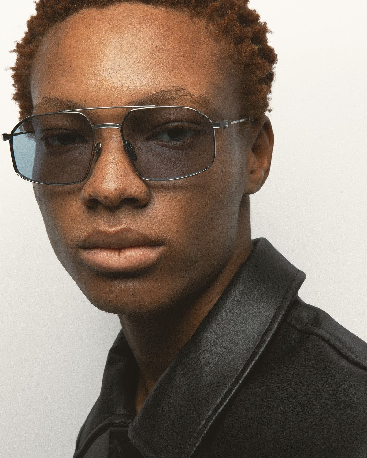 Angle view of model wearing KALEOS Ross Silver Blue Photochromic sunglasses.
