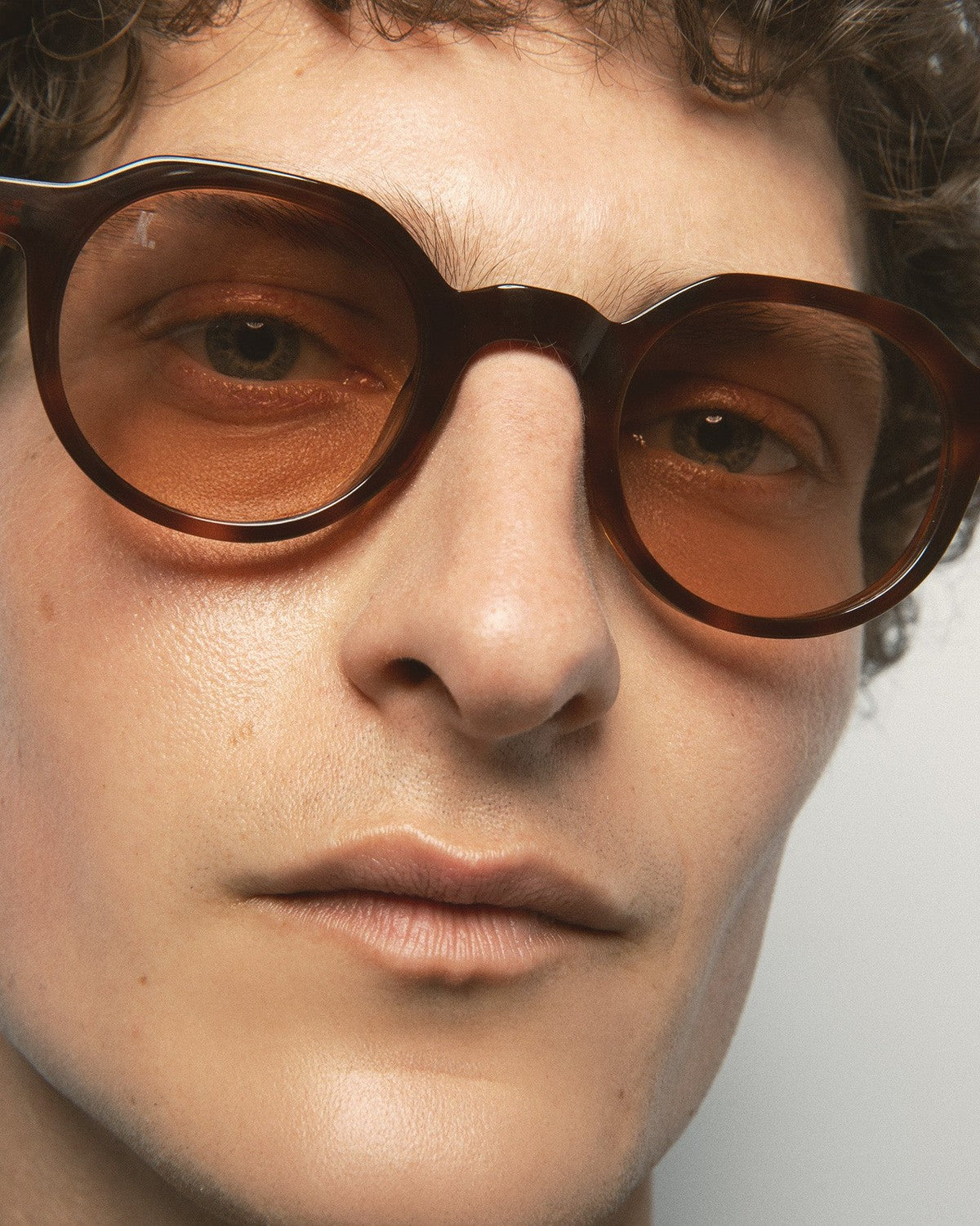 Close-up of model wearing KALEOS Scott Havana Brown sunglasses showing round lenses and frame detail.