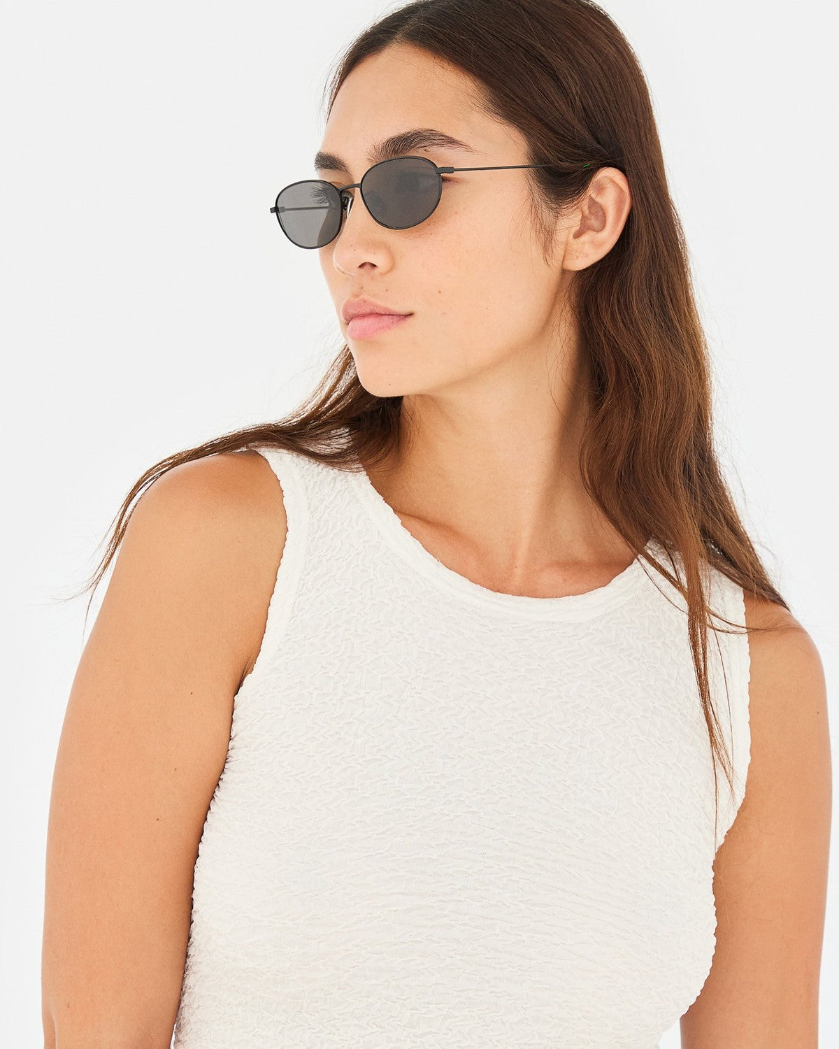 Model wearing RETROSUPERFUTURE Uovo Nero sunglasses with white sleeveless top.