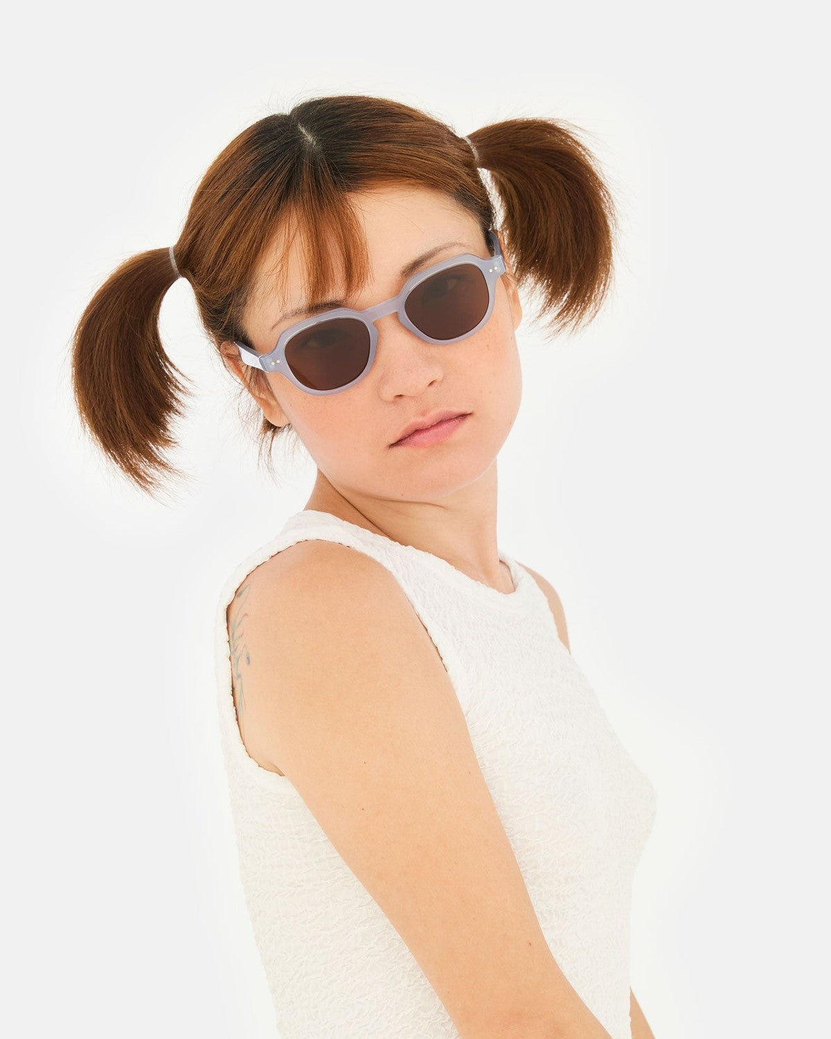 Model with pigtails wearing RETROSUPERFUTURE Voce Light Blue sunglasses and white textured top.