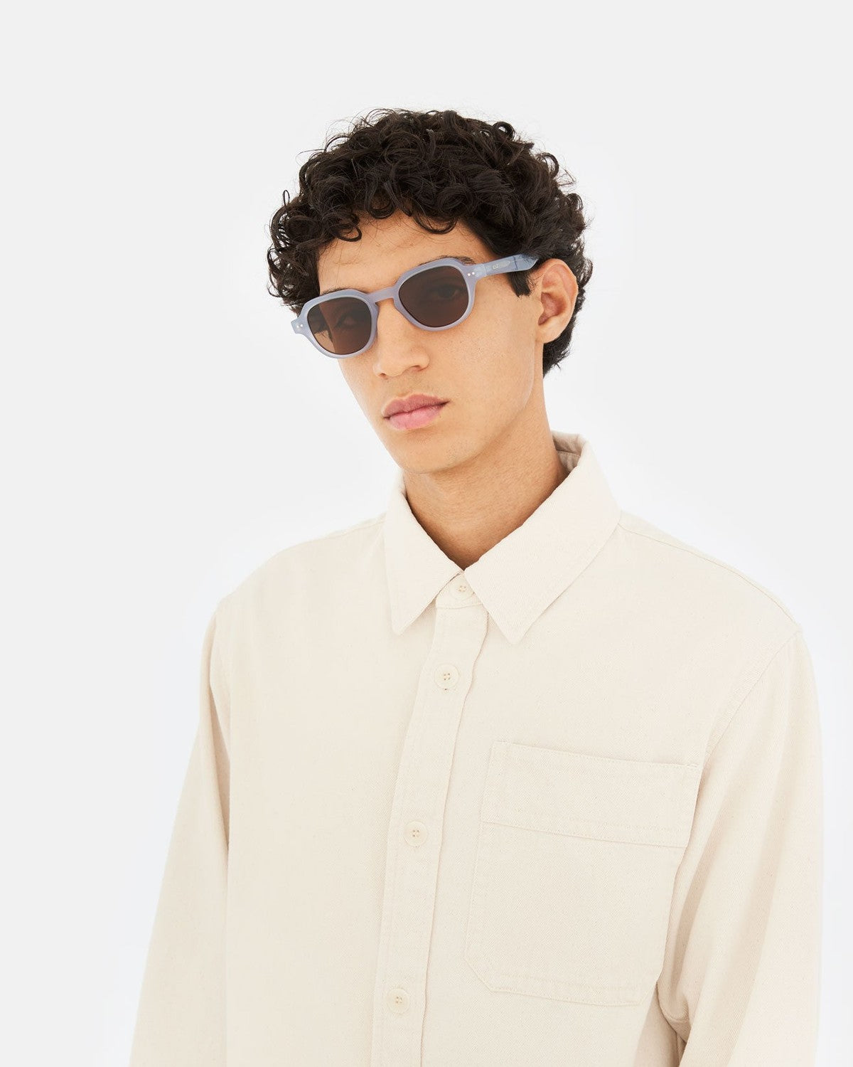 Model in beige shirt wearing RETROSUPERFUTURE Voce Light Blue sunglasses.